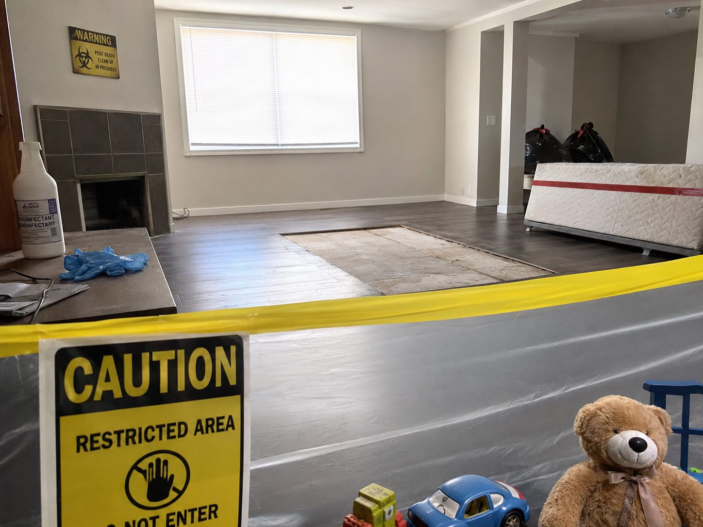 Zone restreinte après un nettoyage après décès avec produits désinfectants, déchets sécurisés et jouets d’enfant au premier plan