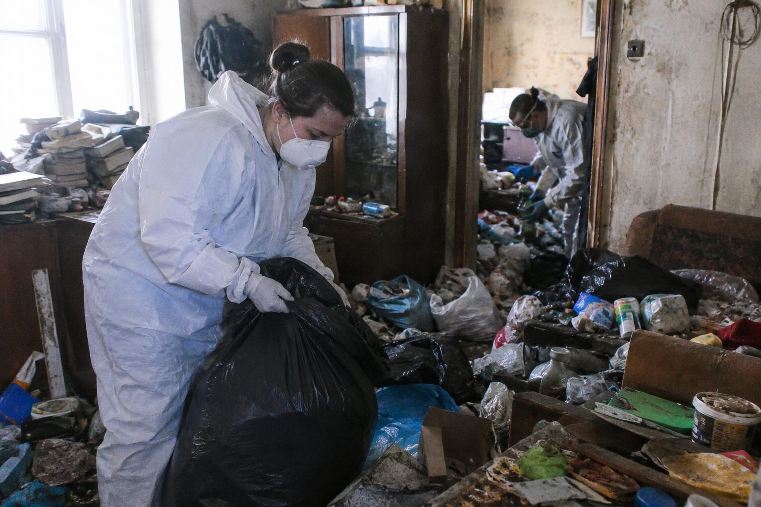 Professionnels en combinaison de protection nettoyant un logement très encombré après un syndrome de Diogène