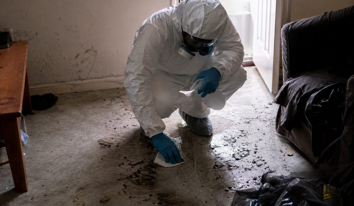 Technicien en combinaison de protection réalisant un nettoyage après décès dans un logement insalubre