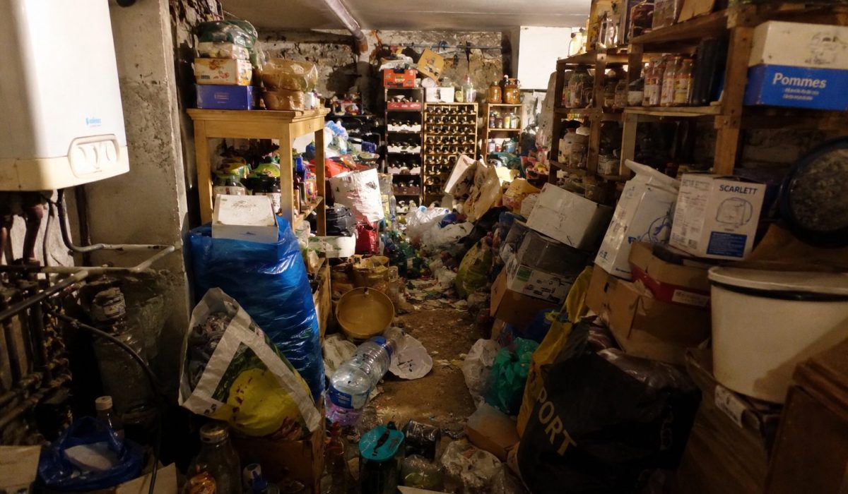 Cave très encombrée avec déchets, cartons et objets accumulés nécessitant un nettoyage après syndrome de Diogène