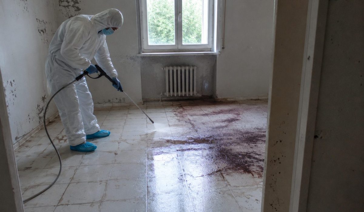Technicien spécialisé en combinaison de protection réalisant un nettoyage après décès dans un logement insalubre