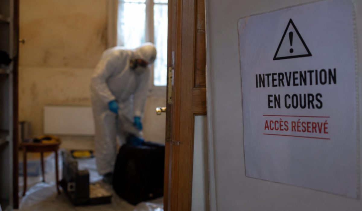 Technicien en combinaison de protection intervenant dans un logement pour un nettoyage après décès avec accès sécurisé