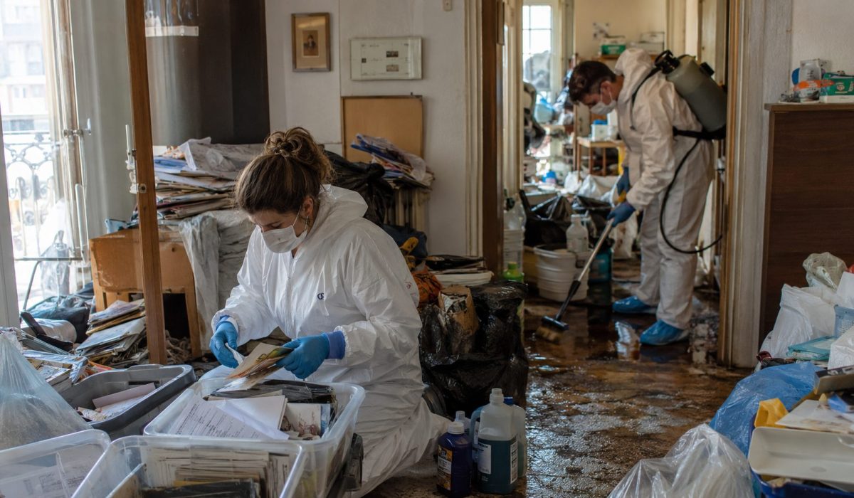 Experts en combinaison de protection triant et nettoyant un logement encombré après un syndrome de Diogène