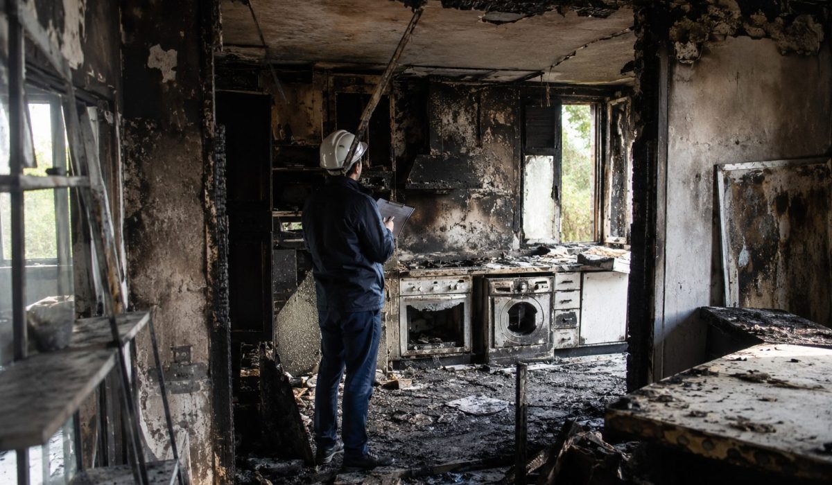 Logement endommagé par un incendie avec un professionnel inspectant les dégâts avant la remise en état