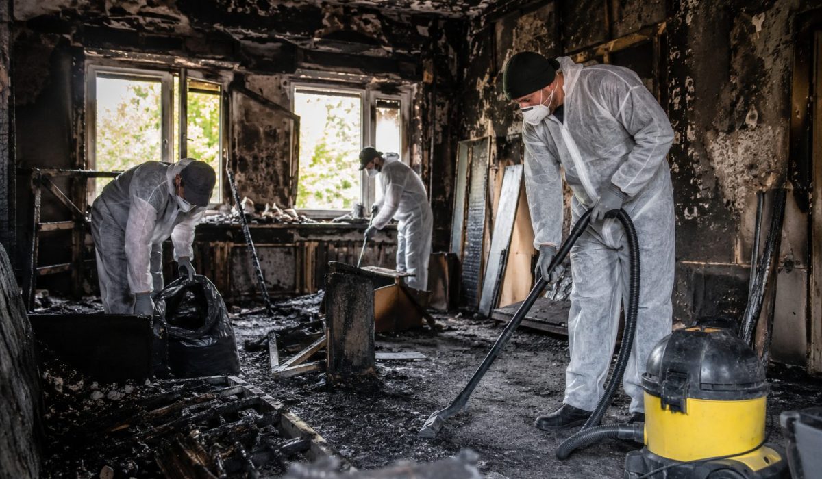 Entreprise spécialisée en nettoyage après incendie intervenant dans une pièce sinistrée avec suie, débris et équipements de protection