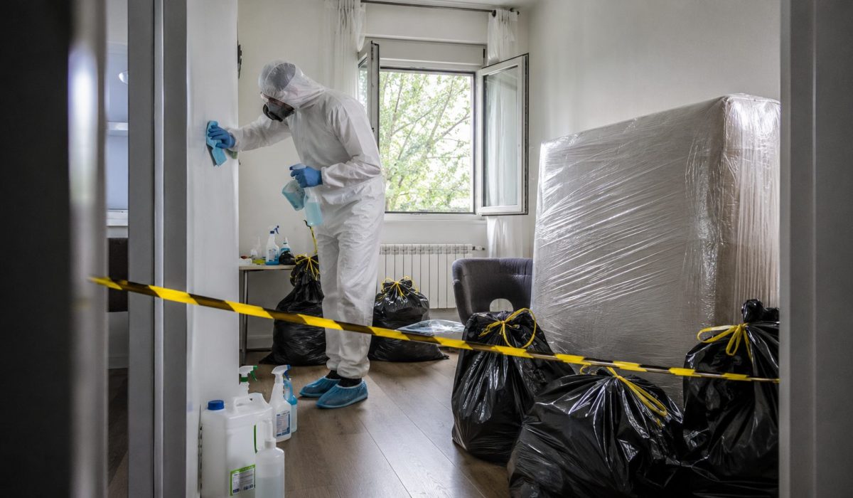 Professionnel en combinaison de protection réalisant un nettoyage après décès dans un logement contaminé