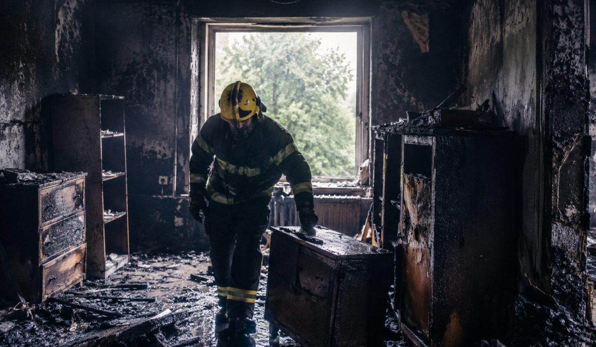 Pompier inspectant des meubles brûlés dans une pièce endommagée par un incendie