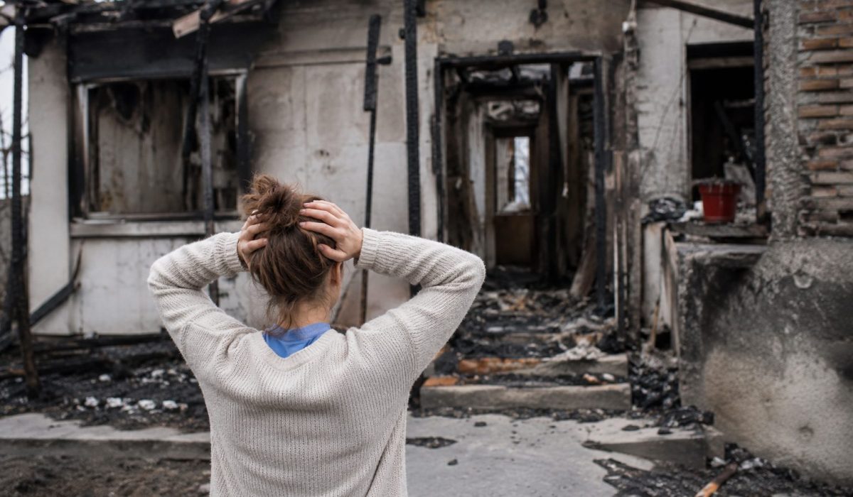 Femme choquée devant son logement détruit par un incendie, illustrant le moment où il faut quitter son habitation pour des raisons de sécurité.