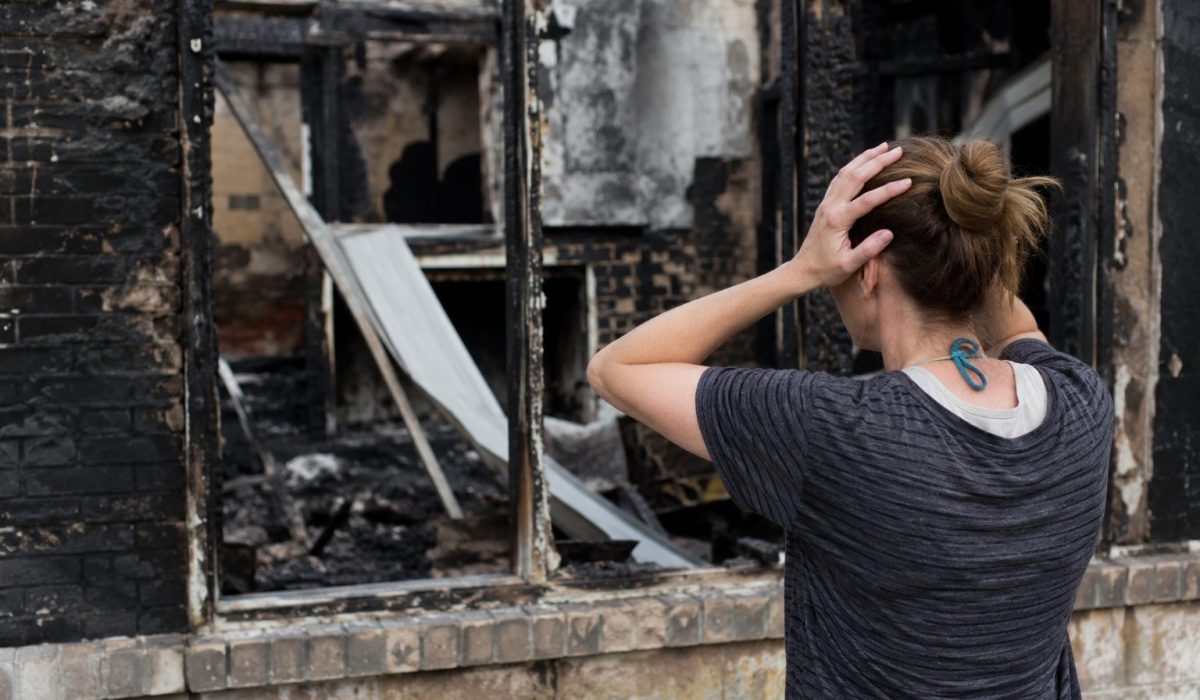Femme choquée devant un logement ravagé par un incendie, illustrant les premières démarches à effectuer après un sinistre.